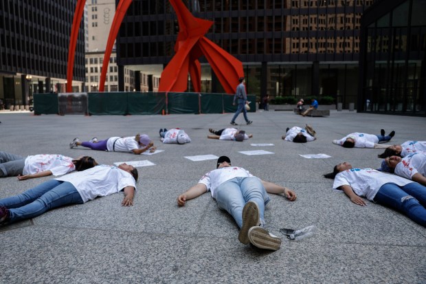 People stage a die-in at Federal Plaza during a immigrant healthcare protest on June 21, 2023, in Chicago. The demonstration represents immigrant lives lost by Gov. J.B. Pritzker's decision to stop immigrants from enrolling in new healthcare coverage. (Shanna Madison/Chicago Tribune)