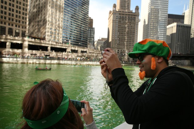 Brent Baines, right, and Neda Jamalirad of Bronzeville take photos after members of the Chicago Journeymen Plumbers Local Union 130 poured green dye into the Chicago River as part of the annual St. Patrick's Day festivities in 2015. (Anthony Souffle/Chicago Tribune)