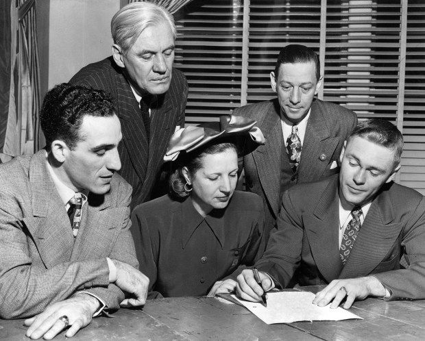 Paul Christman, right, quarterback for the Chicago Cardinals, shows Violet Bidwill, center, owner of the Cardinals, the secret plays with which they hope to beat the Eagles, on Dec. 28, 1947. Cardinals halfback Charles Trippi, bottom left, coach Jim Conzelman, top left, and President Ray Benningsen, look on. (Ed Feeney/Chicago Tribune) 