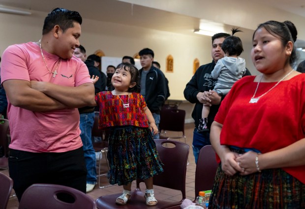 Valentina Xol, 2, plays with her father, Fernando Pec, during a church service for Guatemalan migrants conducted in a native language on Feb. 23, 2025, on the Southwest Side. Valentina's mother, Olga Cuz, is at right. (Brian Cassella/Chicago Tribune)