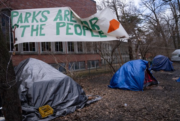 A sign that reads "parks are for the people," is hung on a tree near the tents during an Accelerated Moving Event hosted by the Chicago Department of Family and Support Services for residents of Gompers Park's homeless encampments in Gompers Park on March 5, 2025. (Audrey Richardson/Chicago Tribune)