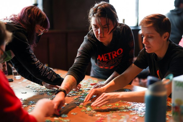 Kassi Cork, from left, Babs Owca, and Haley Engle participate in a monthly puzzle race at Snakes & Lattes Chicago in Logan Square on March 9, 2025. (Eileen T. Meslar/Chicago Tribune)