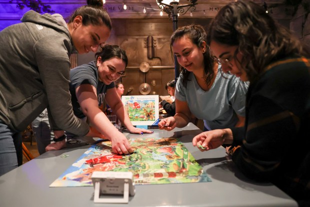 Angela Papa, from left, Maddie Bouchie, Lizzy Alvarez, and Toka Eid compete in a monthly puzzle race at Snakes & Lattes Chicago in Logan Square on March 9, 2025. They went on to win the competition. (Eileen T. Meslar/Chicago Tribune)