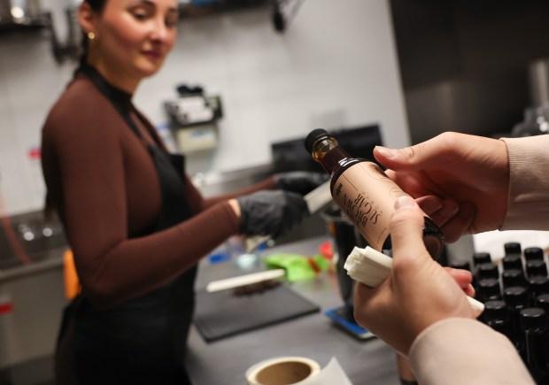 Stefania Marzelia watches as Vikram Patel places labels on one of their syrup bottles at the Sips kitchen on Feb. 27, 2025, in Chicago. Marzelia is an entrepeneur who started her homemade syrups business last year. (Stacey Wescott/Chicago Tribune)