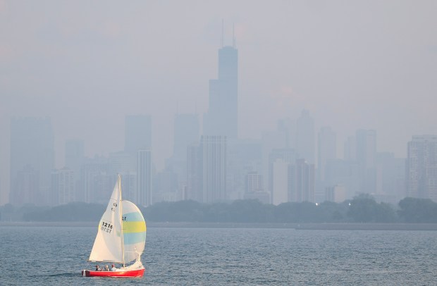 A sailboat passes off of Montrose Point in front of a hazy Willis Tower on July 26, 2023. (Talia Sprague/Chicago Tribune)