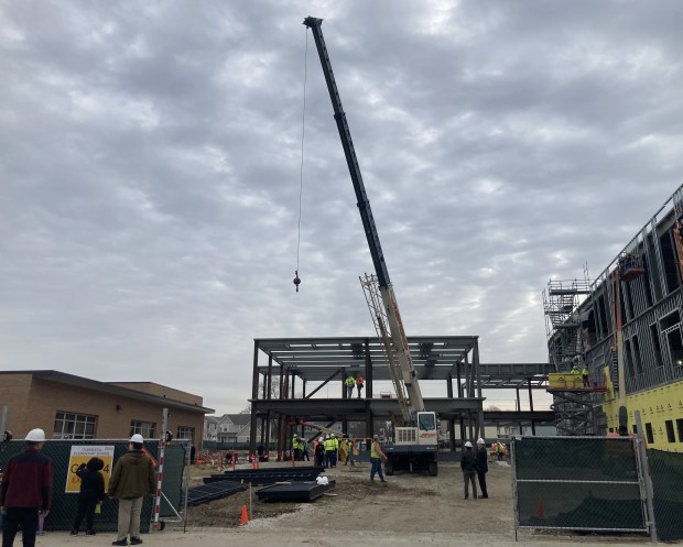 A crane moves away from the building after placing a ceremonial steel beam in place at Forrestal Elementary School in North Chicago. (Steve Sadin/For the Lake County News-Sun)