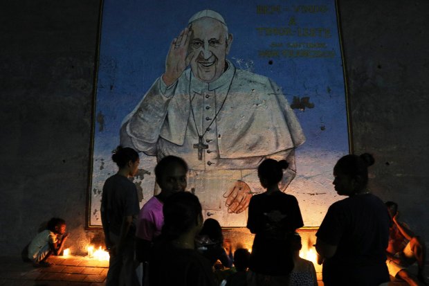 People light candles near a mural of the late Pope Francis during a vigil in Dili, East Timor, Monday, April 21, 2025. (AP)
