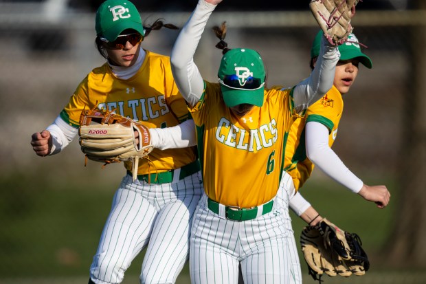 Providence's Angelina Cole, left, Mia Vassalla (6) and Bella Olszta do a little between inning jump during a GCAC game against Mother McAuley in New Lenox on Thursday, April 10, 2025. (Vincent D. Johnson / for the Daily Southtown)
