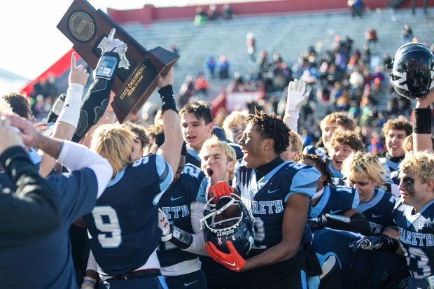 Nazareth's Brendan Flanagan (9) lifts the Class 5A state championship trophy after beating Joliet Catholic at Illinois State's Hancock Stadium in Normal on Saturday, Nov. 25, 2023.