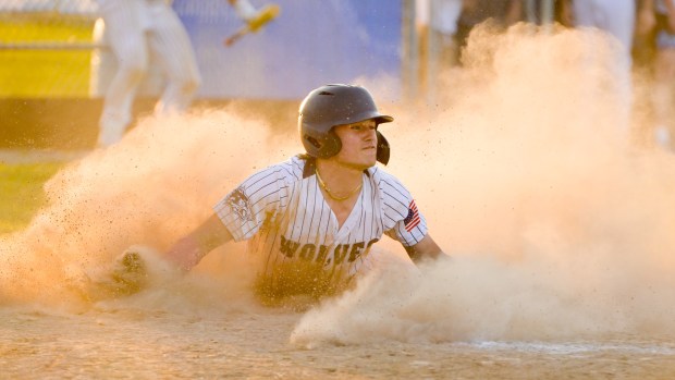 Oswego East's Mason Palermo (9) dives into home to score the winning running on a hit by Niko Villacci during extra innings against Yorkville at home on Tuesday, May 13, 2025. (Mark Black / for the Beacon-News)