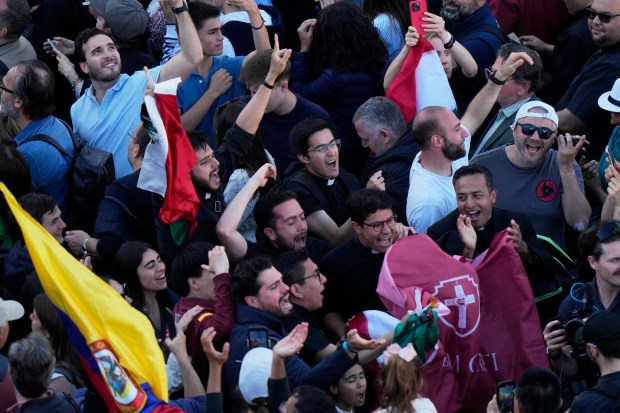 People react as white smoke billows from the chimney of the Sistine Chapel where 133 cardinals are gathering on the second day of the conclave to elect a successor to late Pope Francis, at the Vatican, Thursday, May 8, 2025. (AP Photo/Luca Bruno)