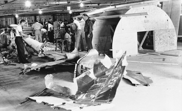 Civil Aeronautics Board investigators are shown as they begin construction of a mock-up of the Continental Airlines 707 jetliner to determine what caused the plane to be ripped apart in a crash that killed 45 people on May 22, 1962. Workers are shown assembling the torn pieces of the plane in preparation for mounting them on a wooden form in the background. (AP)