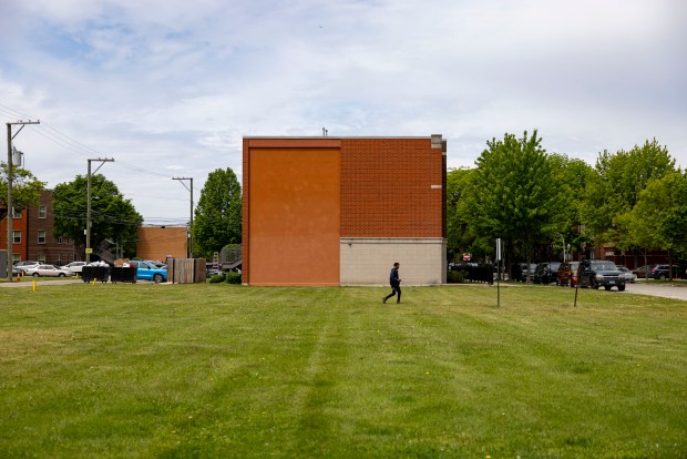 A man cleans trash on vacant land at 1237 W. Grenshaw St. on May 27, 2025, that is part of a section of lots being sold by the Chicago Housing Authority. (Brian Cassella/Chicago Tribune)