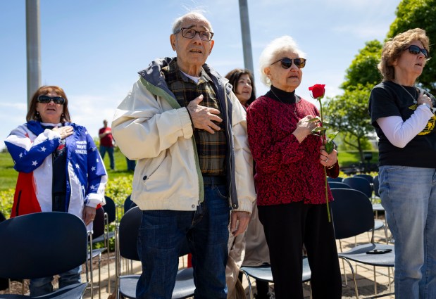 John Curcio, 88, and his wife Anne, 87, recite the pledge of allegiance Sunday, May 25, 2025, during a Memorial Day event DuPage County Veterans' Memorial in Wheaton. Curcio had six older brothers who were veterans including Rudy who was killed in World War II. The memorial, established at the county government center campus in 1999, commemorates DuPage residents killed in military conflicts since the Black Hawk War of 1832. "Memorial Day is for the heroes that are on these plaques," said George Kouba, a member of the group that has organized ceremonies at the site for 23 years. The memorial includes a sundial to acknowledge sacrifice through time and a garden of crosses for those who died most recently in the war on terror. (Brian Cassella/Chicago Tribune)