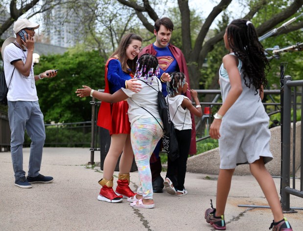 Chicago HOPES for Kids Development Manager Alex Granato, dressed as Supergirl, receives a hug from Aubrey Williams, after the 7-year-old got off the carousel at Lincoln Park Zoo on May 15, 2025. (Chris Sweda/Chicago Tribune)