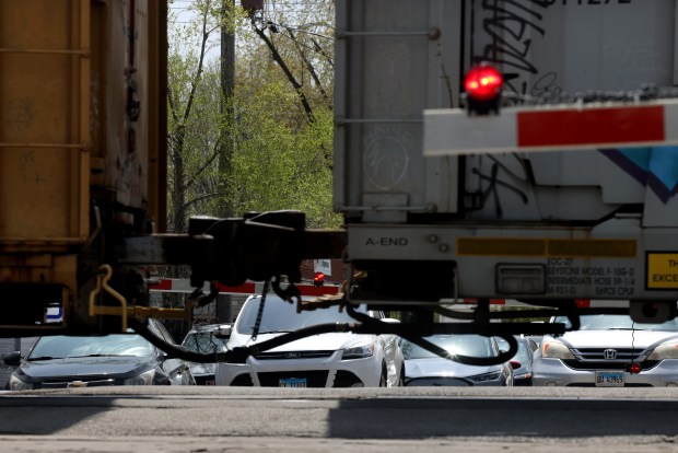 Vehicles wait for a stopped freight train on Seeley Avenue in Dixmoor, April 28, 2025. The village received a grant for a feasibility study to explore solutions to reduce traffic congestion caused by trains that sometimes block crossing for hours. (Antonio Perez/Chicago Tribune)