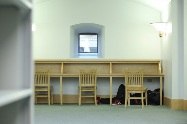 A man sleeps under a desk on the seventh floor of the Harold Washington Library Center on April 2, 2025. (John J. Kim/Chicago Tribune)