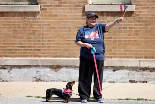 Maria Lopez waves a flag with her dog, Gigi, at the McKinley Park Memorial Day parade, May 26, 2025. (Antonio Perez/Chicago Tribune)