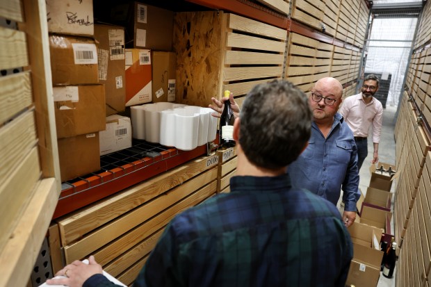 Adam Caldwell, second right, and Patrick Rauber, left, organize wine that the duo stores at Uovo Wine in Chicago on May 1, 2025. (Chris Sweda/Chicago Tribune)