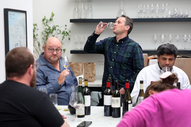 Adam Caldwell, second from left, and Patrick Rauber, third from left, chat with friends while sampling wine at Uovo Wine storage facility in Chicago on May 1, 2025, in preparation for their upcoming Silvaner Summit event. (Chris Sweda/Chicago Tribune)