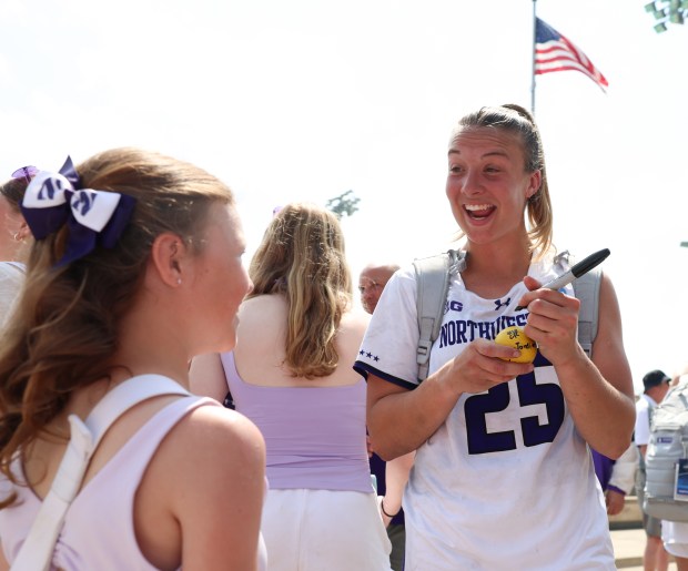 Northwestern midfielder Madison Taylor signs a lacrosse ball for a young fan after the team's 17-12 win over Penn on May 15, 2025, in Evanston. (Stacey Wescott/Chicago Tribune)