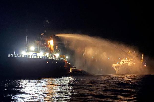 A firefighting-equipped tug boat, left, contacted by the Malta Vessel Traffic Services (VTS) helps controlling a fire occurred on the bow of the Conscience vessel in international waters of the Mediterranean Sea, Friday, May 2, 2025. (Malta Vessel Traffic Services via AP)