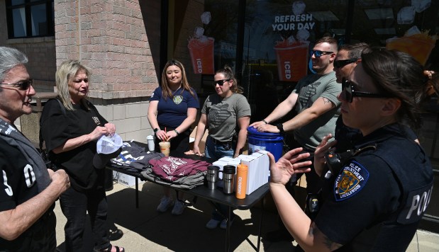 Faith Rago, center, and Frank Rago, right, of Lincolnwood, check in with Lincolnwood Police Department records clerk Sarah Yun and other police personnel at the table the police department set up at a Dunkin' Donuts restaurant in Lincolnwood on May 16, 2025 as part of the "Cop on a Rooftop" fundraiser for Special Olympics Illinois. (Karie Angell Luc/for Pioneer Press)