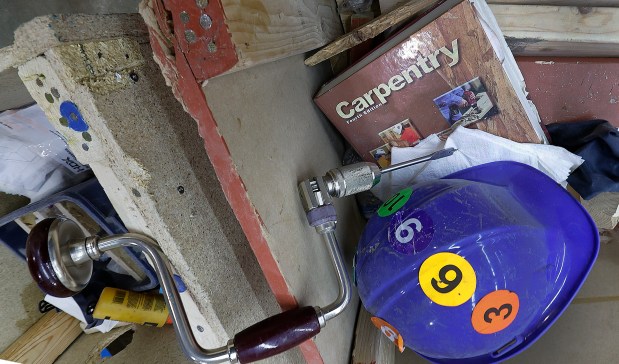 A hand drill, hard hat, and carpentry instruction book lies inside the practice village at the Hammond Career Center on Thursday, May 1, 2025. Four Highland High School seniors will graduate with a carpentry certification and compete nationally in June in Atlanta, Georgia. (John Smierciak / for the Post-Tribune)