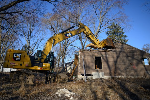 An excavator, operated in part by Gary mayor Eddie Melton, digs into the side of an abandoned building as an additional wave of demolitions begin in Gary's Aetna neighborhood on Monday, March 10, 2025. (Kyle Telechan/for the Post-Tribune)
