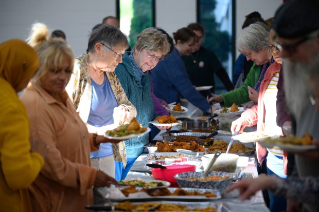 Attendees load their plates with food as local religious leaders and congregants gather to participate in the Northwest Indiana Islamic Center's interfaith potluck event in Crown Point on Friday, May 23, 2025. (Kyle Telechan/for the Post-Tribune)