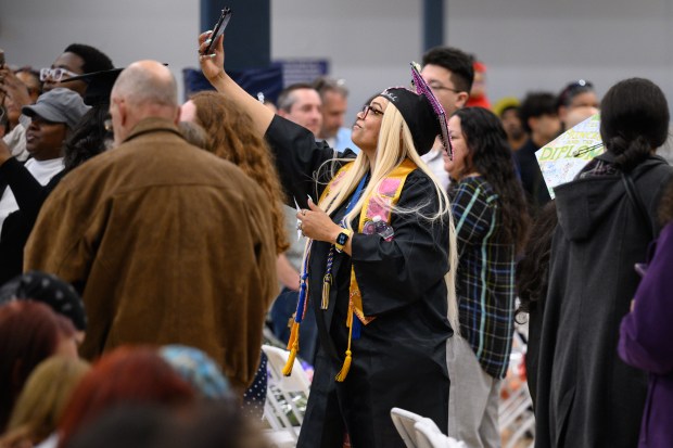 A soon-to-be graduate takes a moment to take a selfie as she makes her way down the aisle during Ivy Tech Lake County's Class of 2025 graduation ceremony in Merrillville on Thursday, May 8, 2025. (Kyle Telechan/for the Post-Tribune)