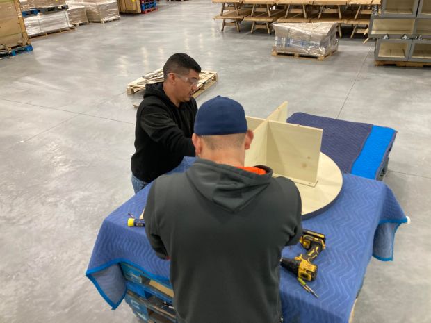 Workers at Morgan Li assemble a retail merchandise display table May 20, 2025, at the company's Chicago Heights warehouse. (Mike Nolan / Daily Southtown)