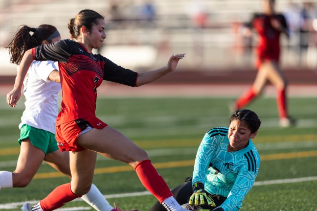 Oak Lawn's keeper Haydee Manriquez dives to stop a ball as Eisenhower's Tania Frausto attacks during a South Suburban Red game in Blue Island on Tuesday, May 13, 2025. (Vincent D. Johnson / for the Daily Southtown)
