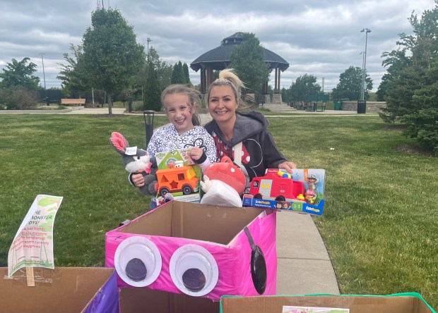 Amelia Burbank, 9, of Homer Glen, and Schilling Elementary School Principal Candis Gasa hold up new toys May 17, 2025, that will benefit children in hospitals. (Michelle Mullins/for the Daily Southtown)