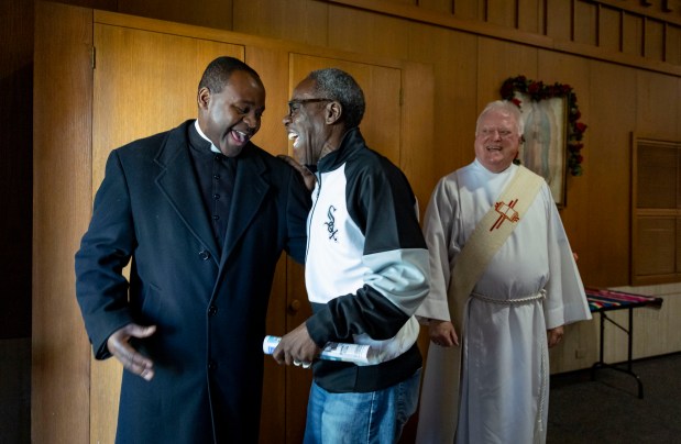 The Rev. Gosbert Rwezahura greets parish member Ronald Sostand as deacon Mel Stasinksi looks on after Mass on May 11, 2025, at Christ Our Savior Catholic Church in South Holland. Sostand wore his White Sox jacket to celebrate the ascension of Pope Leo XIV, who attended St. Mary of the Assumption Parish, which later consolidated with St. Jude to form Christ Our Savior. (Brian Cassella/Chicago Tribune)
