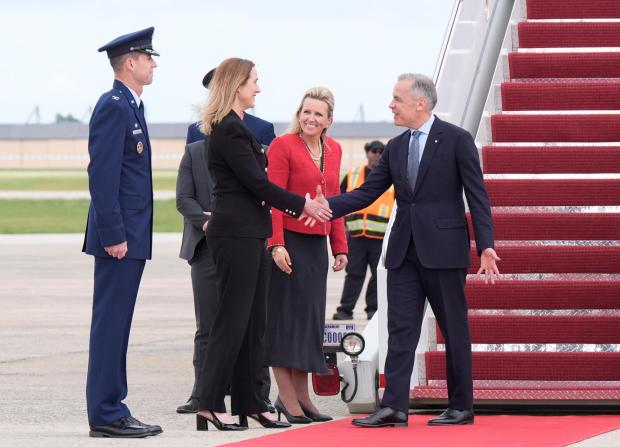 Canadian Prime Minister Mark Carney, right, is greeted by Canadian Ambassador to the U.S. Kirsten Hillman, second left, U.S. Acting Chief of Protocol Abby Jones, and U.S. Col. Randall J. Heusser after he disembarks a government plane