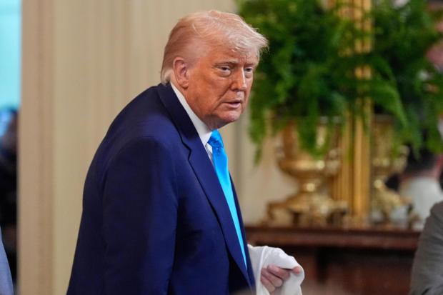 President Donald Trump holds a jersey as he departs after hosting the 2025 NCAA Champion, University of Florida men's basketball team in the East Room of the White House, Wednesday, May 21, 2025, in Washington. (AP Photo/Julia Demaree Nikhinson)