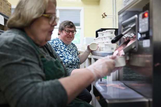 Lauren Miller, right, puts tops on cups of strawberry ice cream that Susanne Spahn, left, fills at Lambs Farm on May 20, 2025, in Libertyville. Lambs Farm is a sprawling farm with a petting zoo, restaurant, bakery, pet store, thrift store, and living facilities for developmentally disabled adults. (Stacey Wescott/Chicago Tribune)
