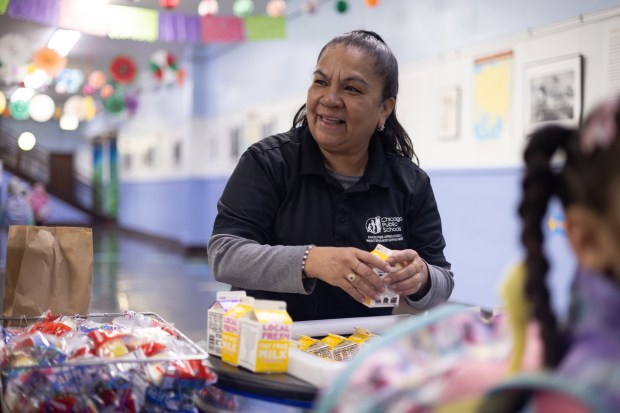 Micaela Ortiz Arredondo hands out free breakfast for students before class begins at 8:15 a.m. at Hibbard Elementary School on May 2, 2025. (Audrey Richardson/Chicago Tribune)