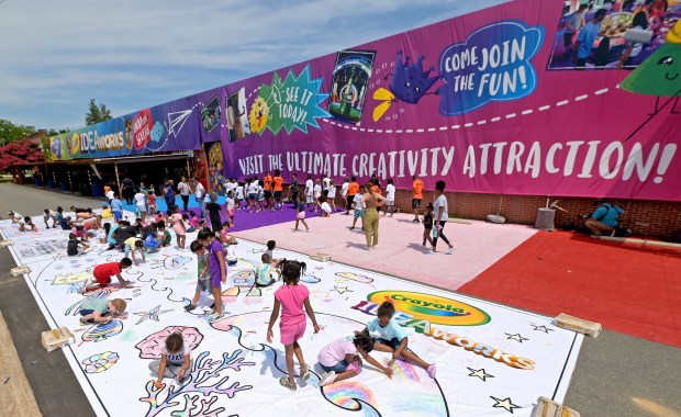 Children use crayons to color in the world's largest coloring page at Camp North End in July, 2022, in Charlotte, North Carolina. (Jeff Siner/The Charlotte Observer)