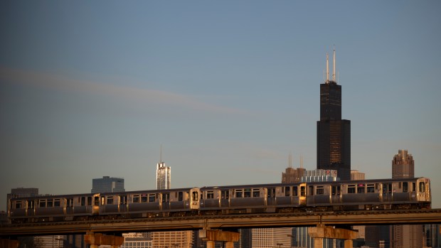 A Loop-bound Pink Line train passes in front of the Chicago skyline after departing the 18th Street CTA station in Pilsen on Dec. 12, 2023. (Talia Sprague/Chicago Tribune)