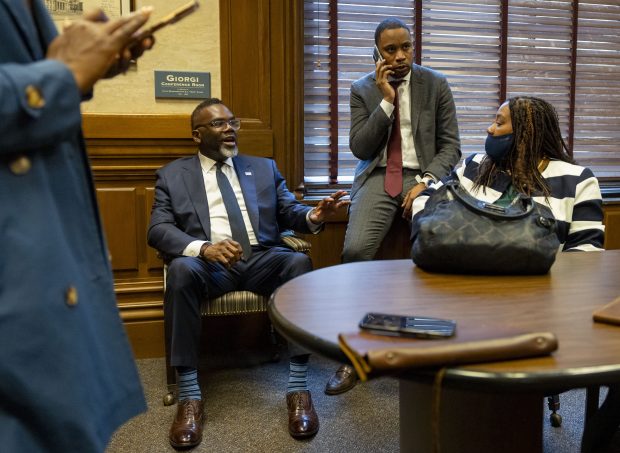Mayor Brandon Johnson talks with budget director Annette Guzman, right, while senior adviser Jason Lee, second from right, takes a phone call between meetings with lawmakers at the Illinois State Capitol on April 30, 2025, in Springfield. (Brian Cassella/Chicago Tribune)