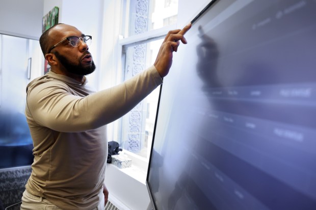 Male Mogul Initiative founder Walter Mendenhall looks over the status of various projects at the company's Madison Street office on April 22, 2025. (Terrence Antonio James/Chicago Tribune)