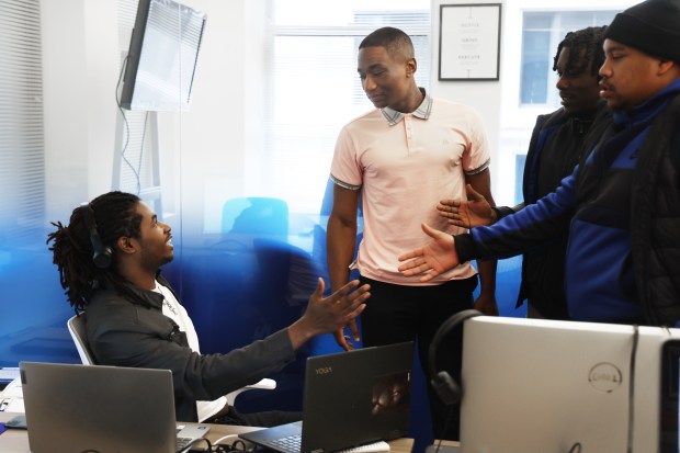 Jayshawn Ferguson, left, and Jeremiah Swint, center, discuss a client's business loan options at Male Mogul Initiative on April 22, 2025. (Terrence Antonio James/Chicago Tribune)