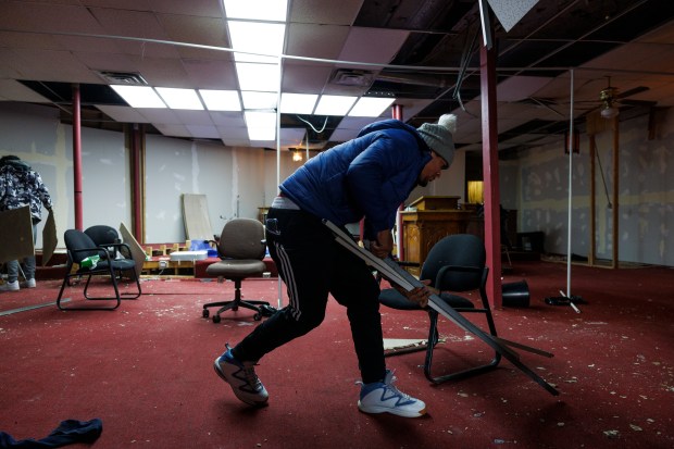 Rayni Cuadrado, 29, of Venezuela cleans debris off the floor of the New Promiseland Missionary Baptist Church after it was broken into in the North Lawndale neighborhood on Jan. 11, 2024. Cuadrado who had been going to Home Depot every day for a month, said it was his first substantial job after arriving in the U.S in November. (Armando L. Sanchez/Chicago Tribune)
