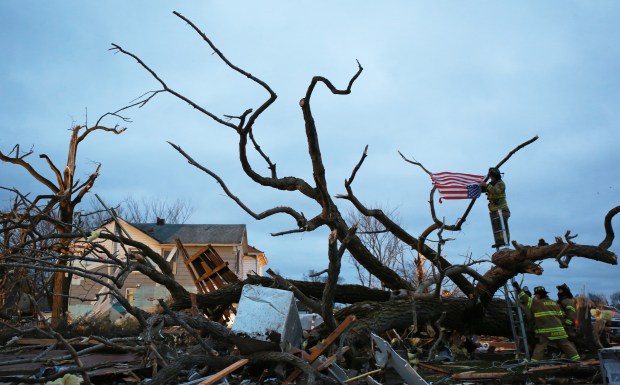 Firefighters tie a U.S. flag to a fallen tree limb at dawn, April 10, 2015, after a tornado destroyed much of the town of Fairdale the previous night. (John J. Kim/Chicago Tribune)