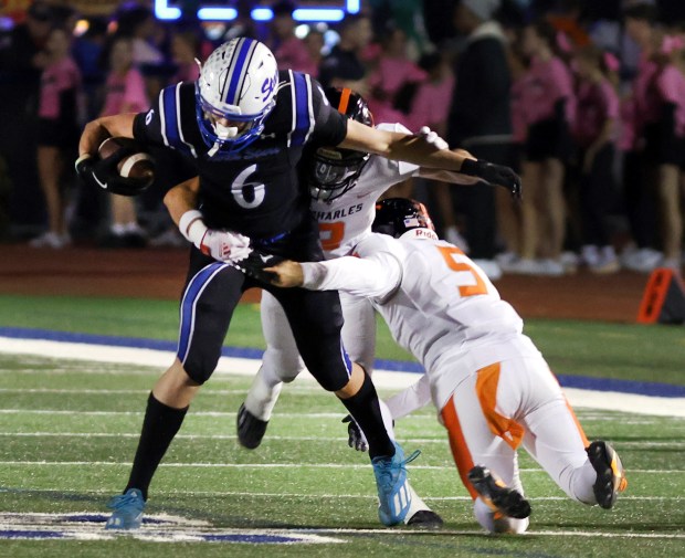 St. Charles North's Keaton Reinke (6) runs the ball as St. Charles East Sean Keegan (5) and Anthony Gutierrerz (2) defend during game in St. Charles on Friday, Oct. 4, 2024. (James C. Svehla / Beacon News)