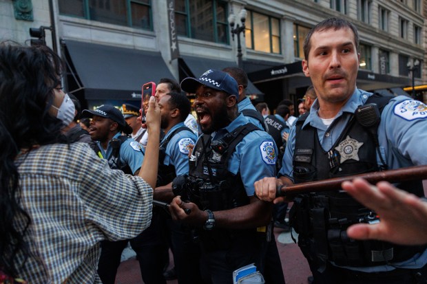 People argue with officers after watching police detain several people while activists march in the Loop after protests took place across the country following recent ICE raids on immigrant communities Tuesday June 10, 2025, in Chicago. (Armando L. Sanchez/Chicago Tribune)
