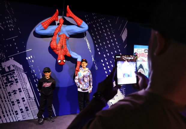 Alex Bolghand, foreground, photographs his sons Wyatt, left, 7, and Leo, 10, at the exhibition "Marvel's Spider-Man: Beyond Amazing" at the Griffin Museum of Science and Industry on May 22, 2025. The family was visiting Chicago from San Carlos, California. (Terrence Antonio James/Chicago Tribune)
