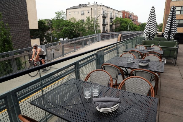 A bicyclist rides past the upper-level patio of Wolf & Company at 1752 N. Western Ave. in Chicago on June 12, 2025. The restaurant has access to The 606 trail. (Terrence Antonio James/Chicago Tribune)
